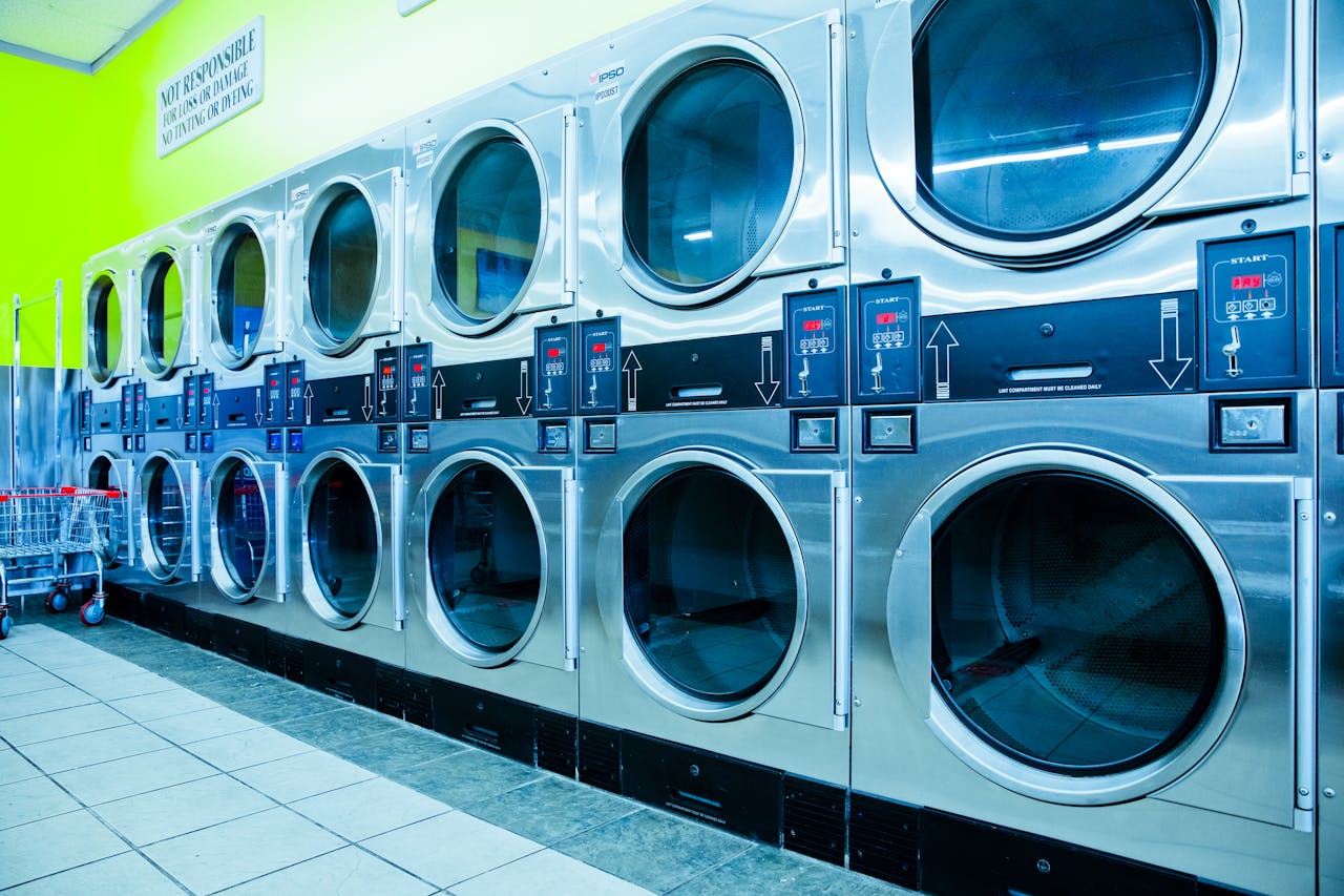 Home Bright laundromat with rows of industrial washing machines and vibrant green walls.
