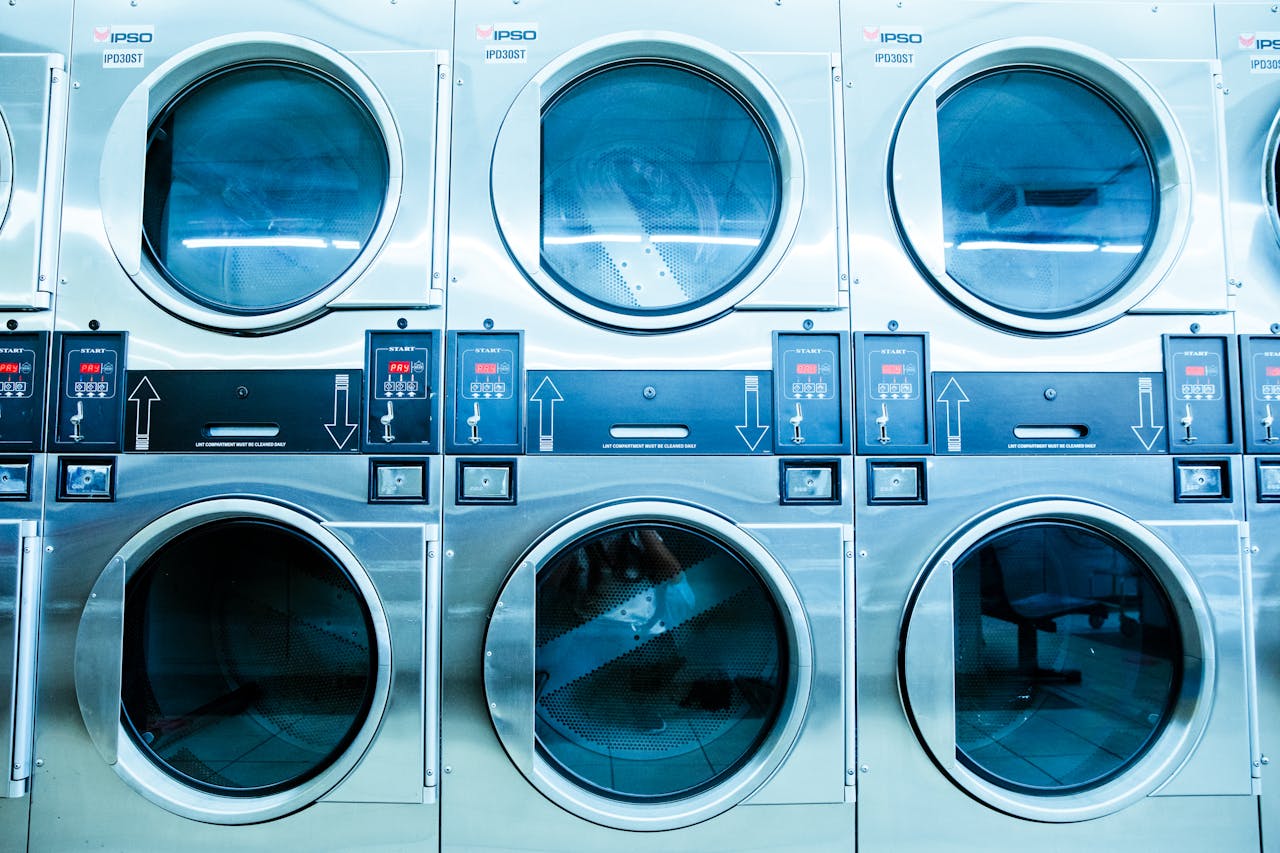 Home A row of modern washing machines in a launderette, showcasing contemporary laundry technology.